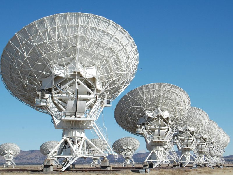 Array of radio telescopes at the Very Large Array in New Mexico under a clear blue sky.