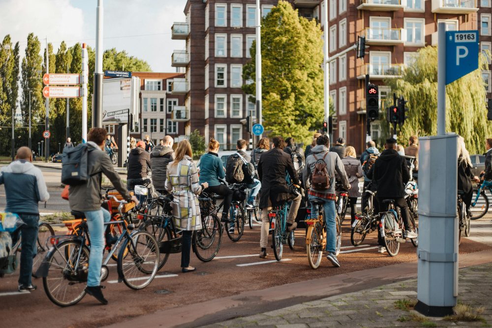 Group of urban cyclists waiting at a traffic light on a busy city street.
