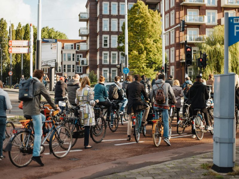 Group of urban cyclists waiting at a traffic light on a busy city street.