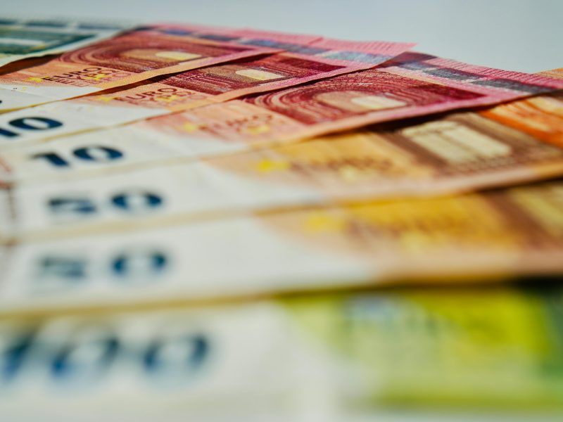 A close-up image of euro banknotes in various denominations spread out, showcasing currency details.